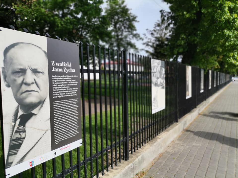 Tytułowa plansza wystawy ulicznej z napisem Z WALIZKI JANA ZYCHA, widoczna twarz mężczyzny