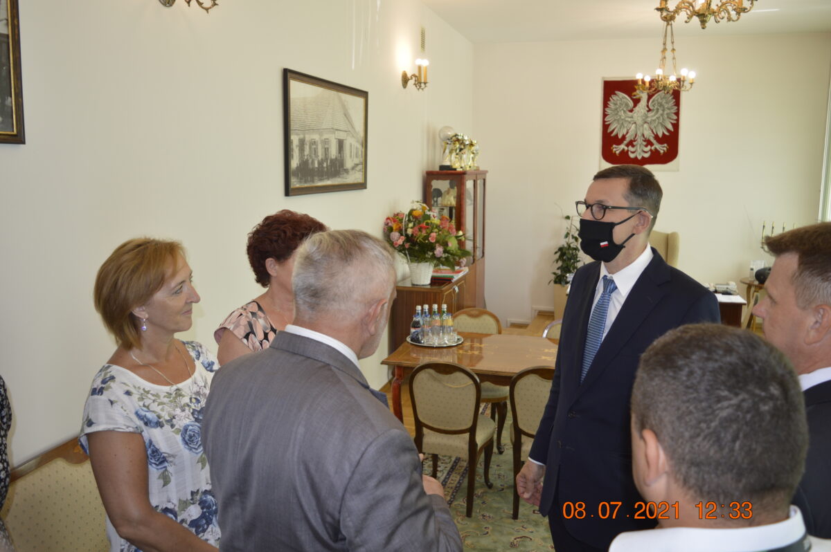 Grupa osób w gabinecie w tle Godło Polki