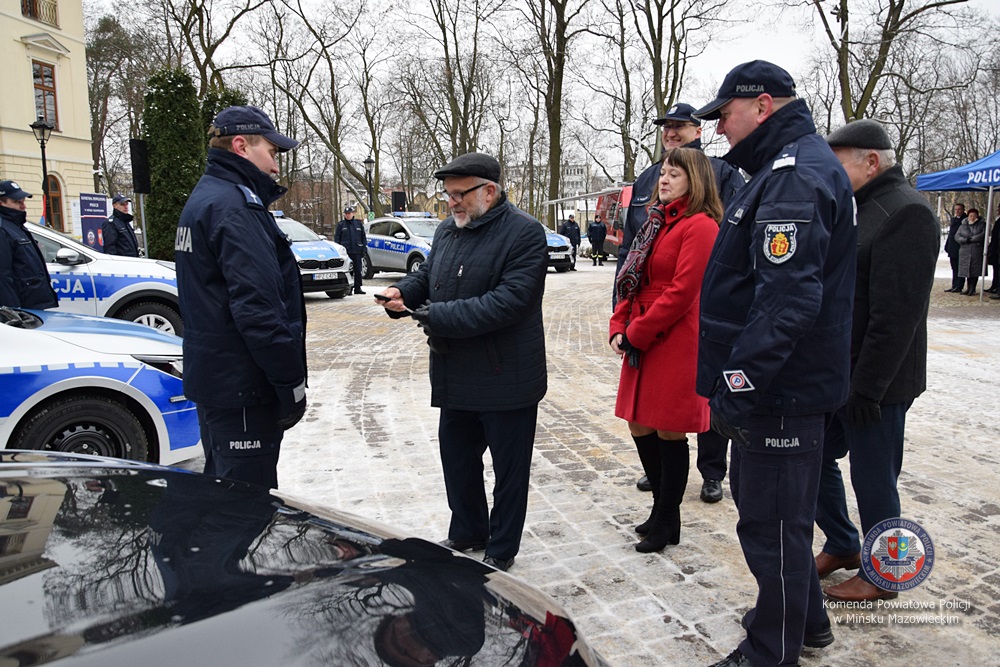 Kilka osób przy samochodzie policyjnym