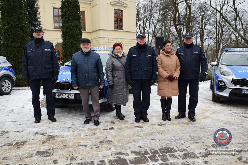 Kilka osób przy samochodzie policyjnym