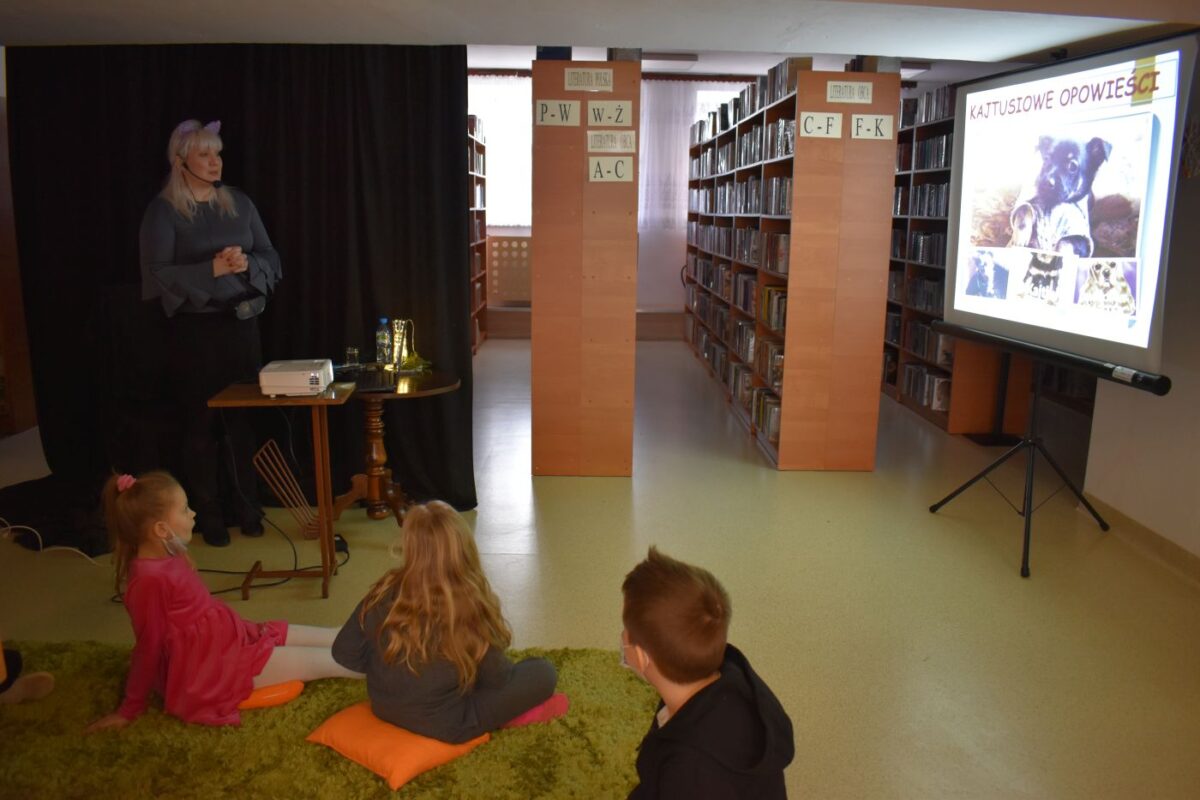 W bibliotece grupka dzieci z kolorowymi noskami za nimi regały z książkami
