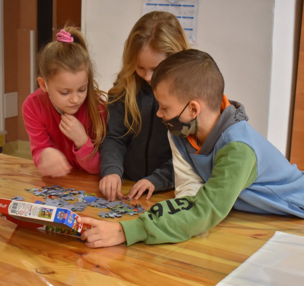 W bibliotece grupka dzieci z kolorowymi noskami za nimi regały z książkami