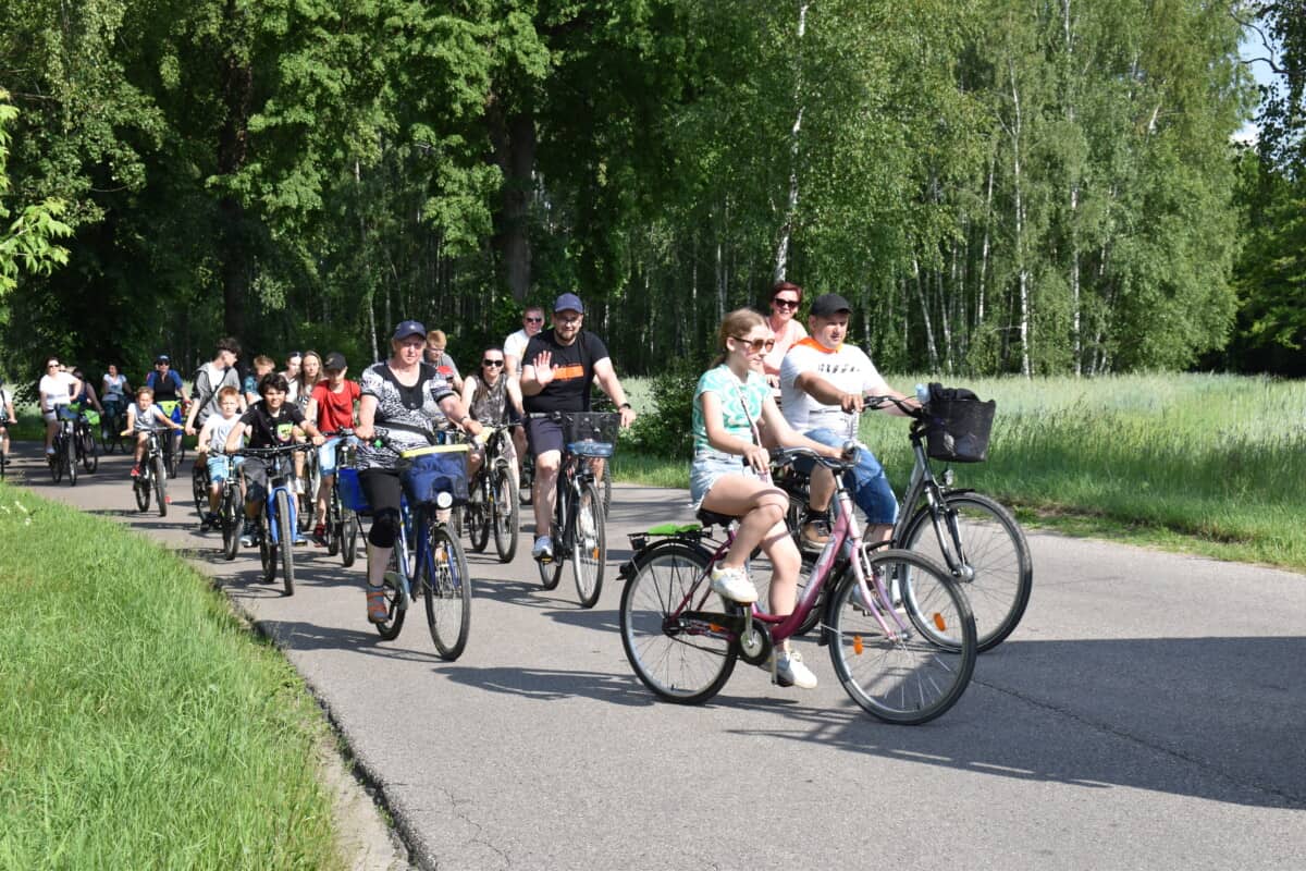 Rowerzyści jadą pomiędzy lasem i polami