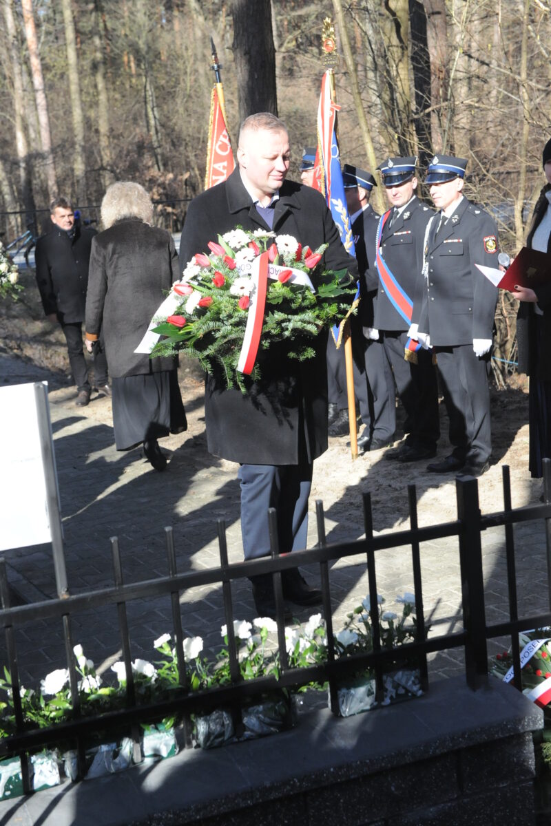 Na obrazku widocznym grupy ludzi stojących na cmentarzu. Są ubrani na czarno, co miesiąc, że mogą wziąć udział w uroczystości pogrzebowej.