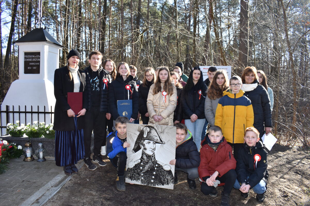 Naruszone jest grupa osób pozujących do zdjęcia przed grobem. Wyrażają pamięć i pamięć o zmarłym, utrwalając dziesięć momentów na fotografii.