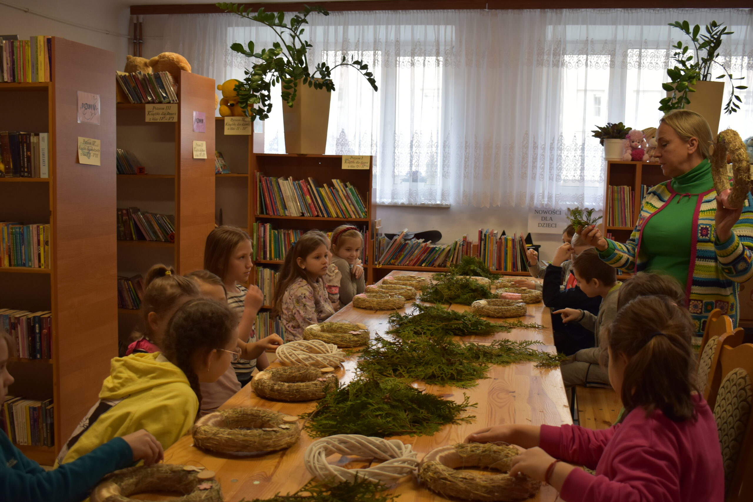 Na widocznych są dzieci uczestniczące w warsztatach plastikowych prowadzonych w bibliotece. Instruktor wykonawczy, który przeszedł w realizacji ich działania.