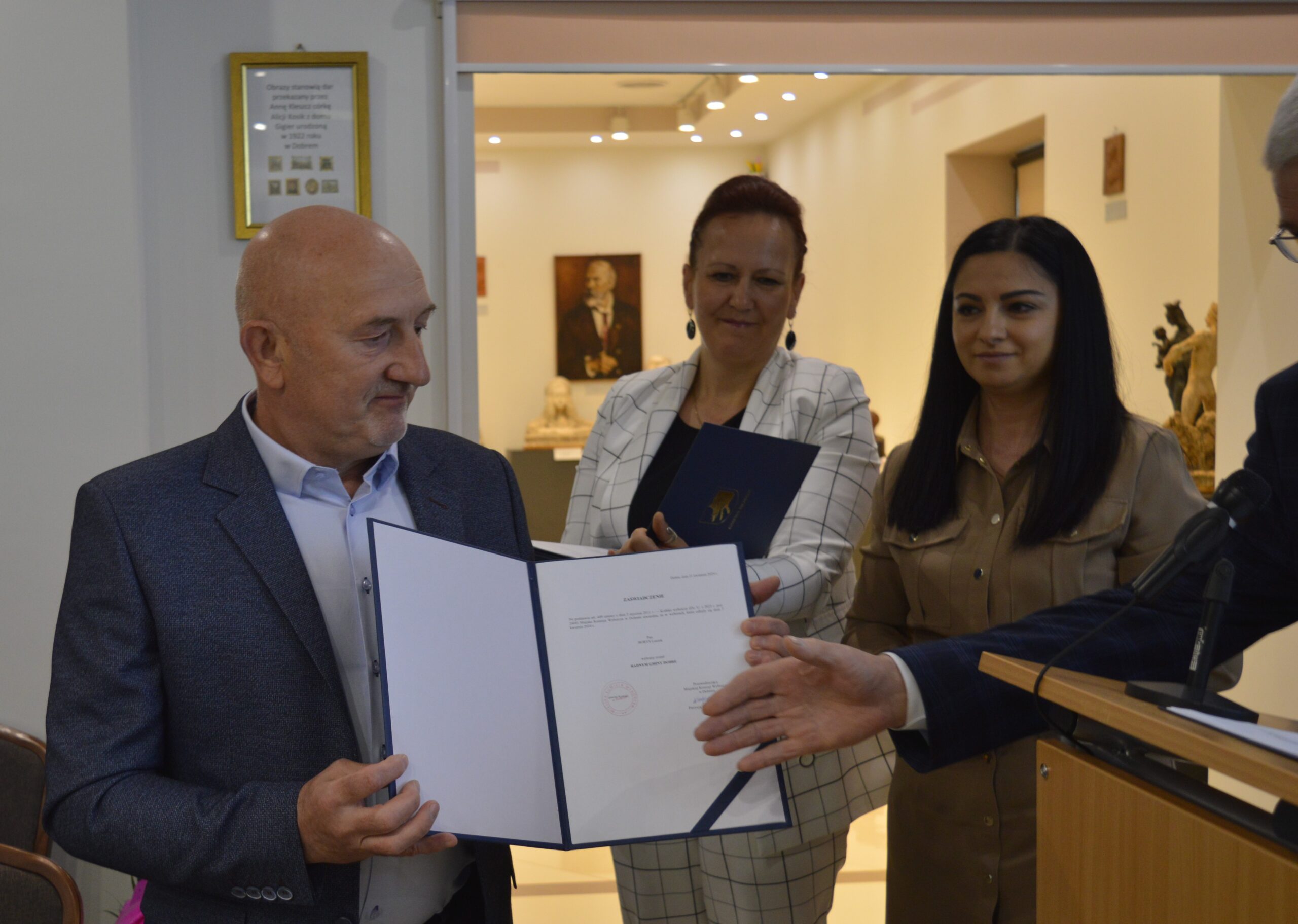 Na dowód formalną ceremonię wręczenia certyfikatu mężczyznom, podczas których dwie kobiety są monitorowane. Pokój, w którym znajduje się miejsce, w którym znajdują się udekorowane szklane gablotami oraz składniki dzieła sztuki.