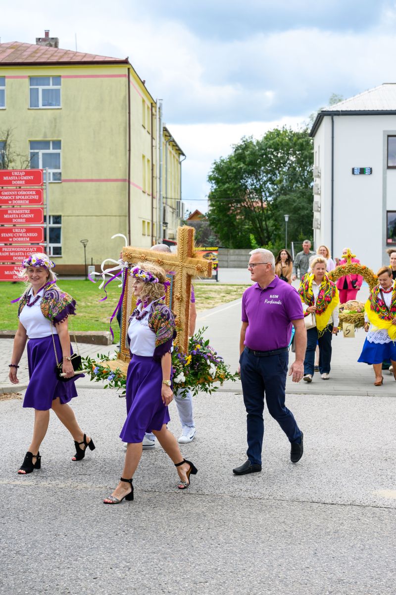 Na zdjęciu widoczna jest procesja z figurą zbożowego krzyża. Osoby w strojach ludowych niosą dekoracje kwiatowe. Piękny, słoneczny dzień.